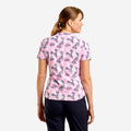 A woman shown from the back wearing a short-sleeve pink scrub top with a dark gray butterfly pattern, paired with navy pants, against a light gray background.