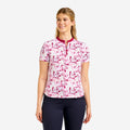 A woman modeling a short-sleeve golf polo shirt with a pink and white floral pattern and a dark pink collar and zipper placket, paired with dark navy pants, against a light gray background.